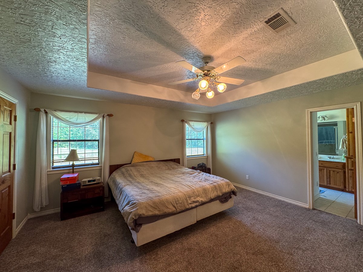 37 Archie Road Huntsville, TX 77320 - Photo 14 of 40 a spacious bedroom with a bed and a chandelier