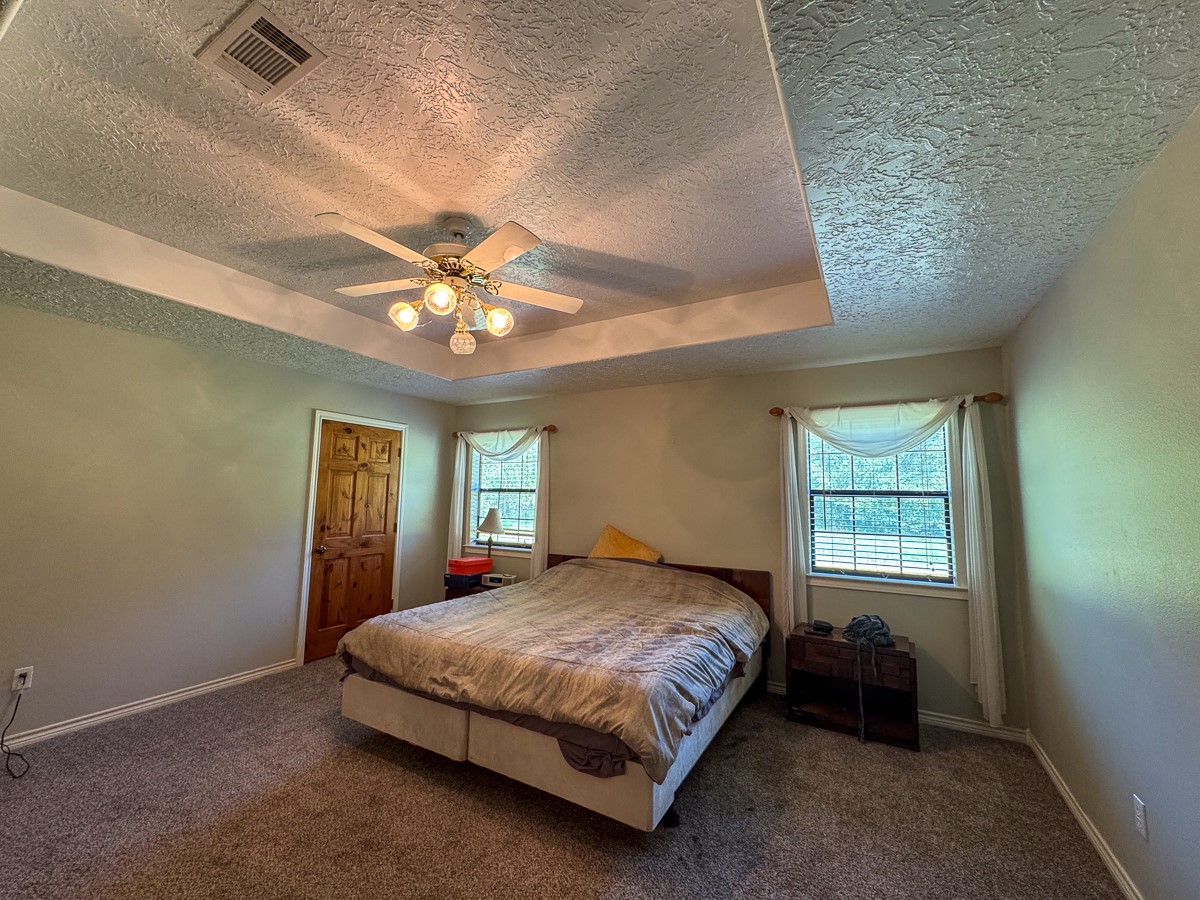 37 Archie Road Huntsville, TX 77320 - Photo 15 of 40 a bedroom with a large bed chandelier and a window