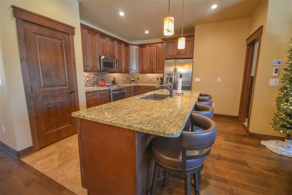 835 Independence Road, Unit 6B Keystone, CO 80435 - Photo 14 of 30 a kitchen with granite countertop kitchen island stainless steel appliances a dining table chairs sink and wooden floor
