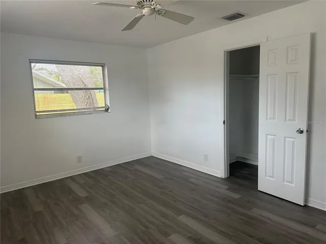 an empty room with wooden floor and a ceiling fan