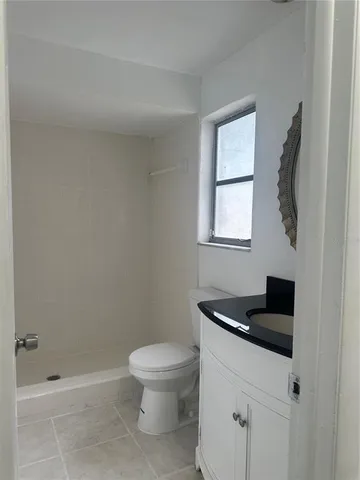 a bathroom with a granite countertop sink a toilet and shower