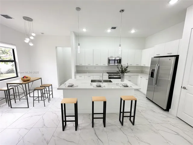 a kitchen with kitchen island a appliances dining table and chairs