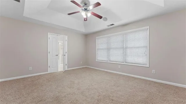 an empty room with chandelier fan and windows