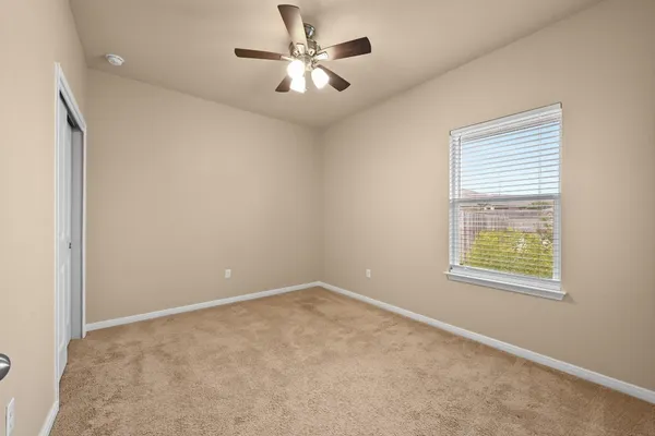 an empty room with windows and fan