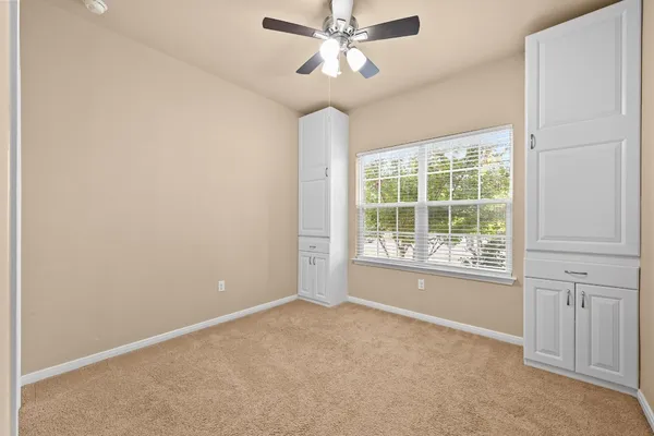 an empty room with windows and fan