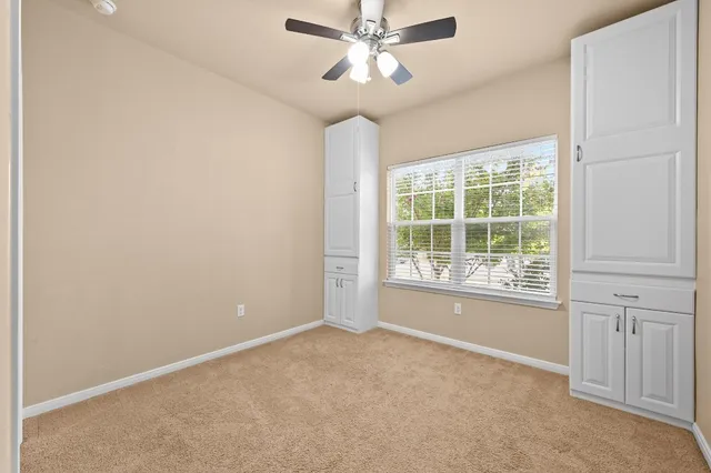 an empty room with windows and fan