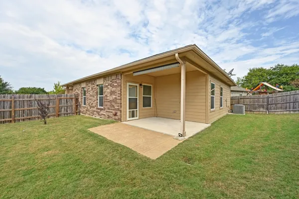 a view of backyard of house with wooden fence