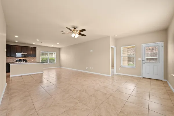a view of an empty room with kitchen and chandelier