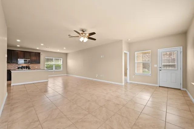 a view of an empty room with kitchen and chandelier