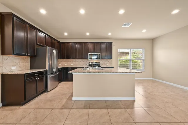 a large kitchen with stainless steel appliances granite countertop a stove a sink a microwave and a refrigerator