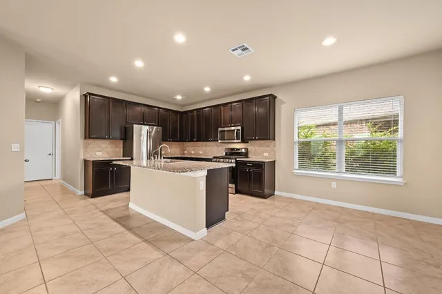 a kitchen with stainless steel appliances granite countertop a stove top oven a sink and a refrigerator