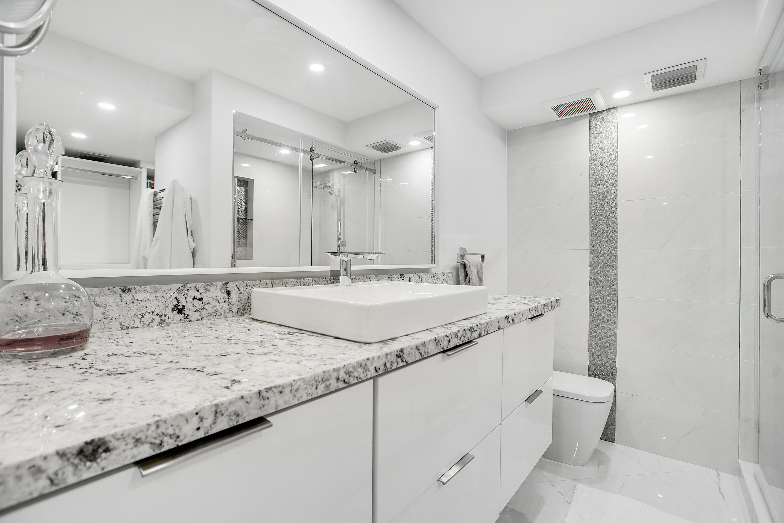 501 Southwest 11th Place, Unit 317 Boca Raton, FL 33432 - Photo 7 of 28 a bathroom with a granite countertop sink a toilet and a large mirror