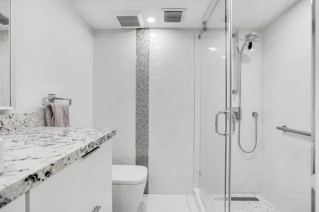 a bathroom with a granite countertop sink toilet and shower