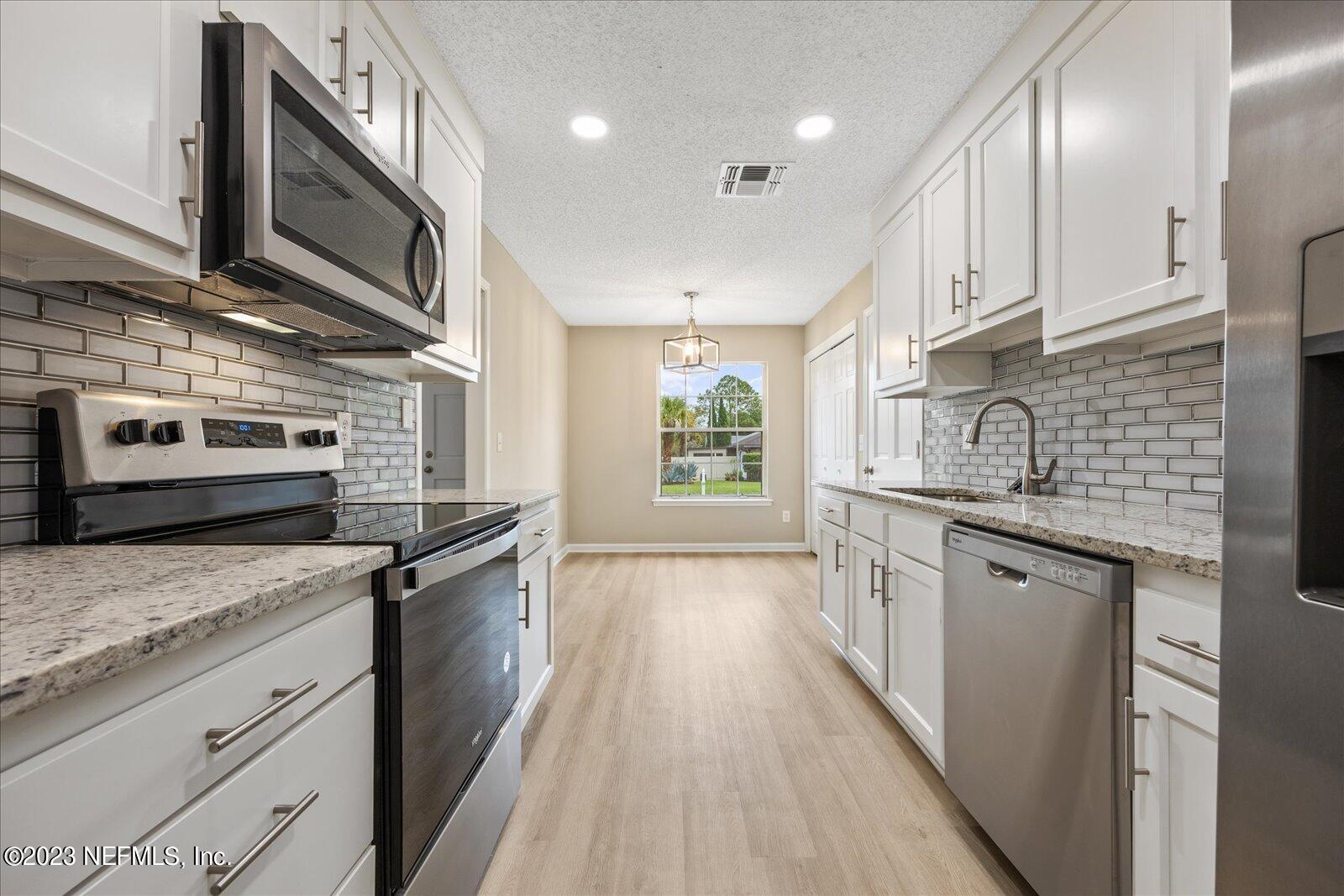 1566 Rusty Rail Road Jacksonville, FL 32225 - Photo 25 of 45 a kitchen with stainless steel appliances granite countertop wooden cabinets a stove top oven a sink and dishwasher