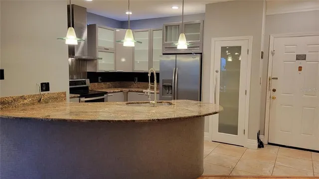 a kitchen with kitchen island granite countertop a sink and a refrigerator