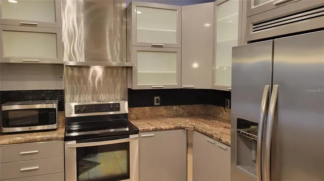 a kitchen with stainless steel appliances granite countertop a refrigerator a stove and a sink with wooden floor