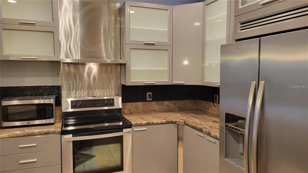 5168 Northridge Road, Unit 106 Sarasota, FL 34238 - Photo 5 of 33 a kitchen with stainless steel appliances granite countertop a refrigerator a stove and a sink with wooden floor