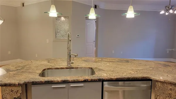 a kitchen with kitchen island granite countertop a sink a counter top and a chandelier