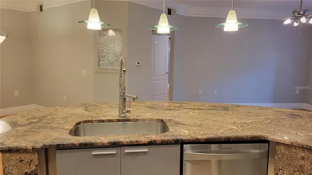 a kitchen with kitchen island granite countertop a sink a counter top and a chandelier