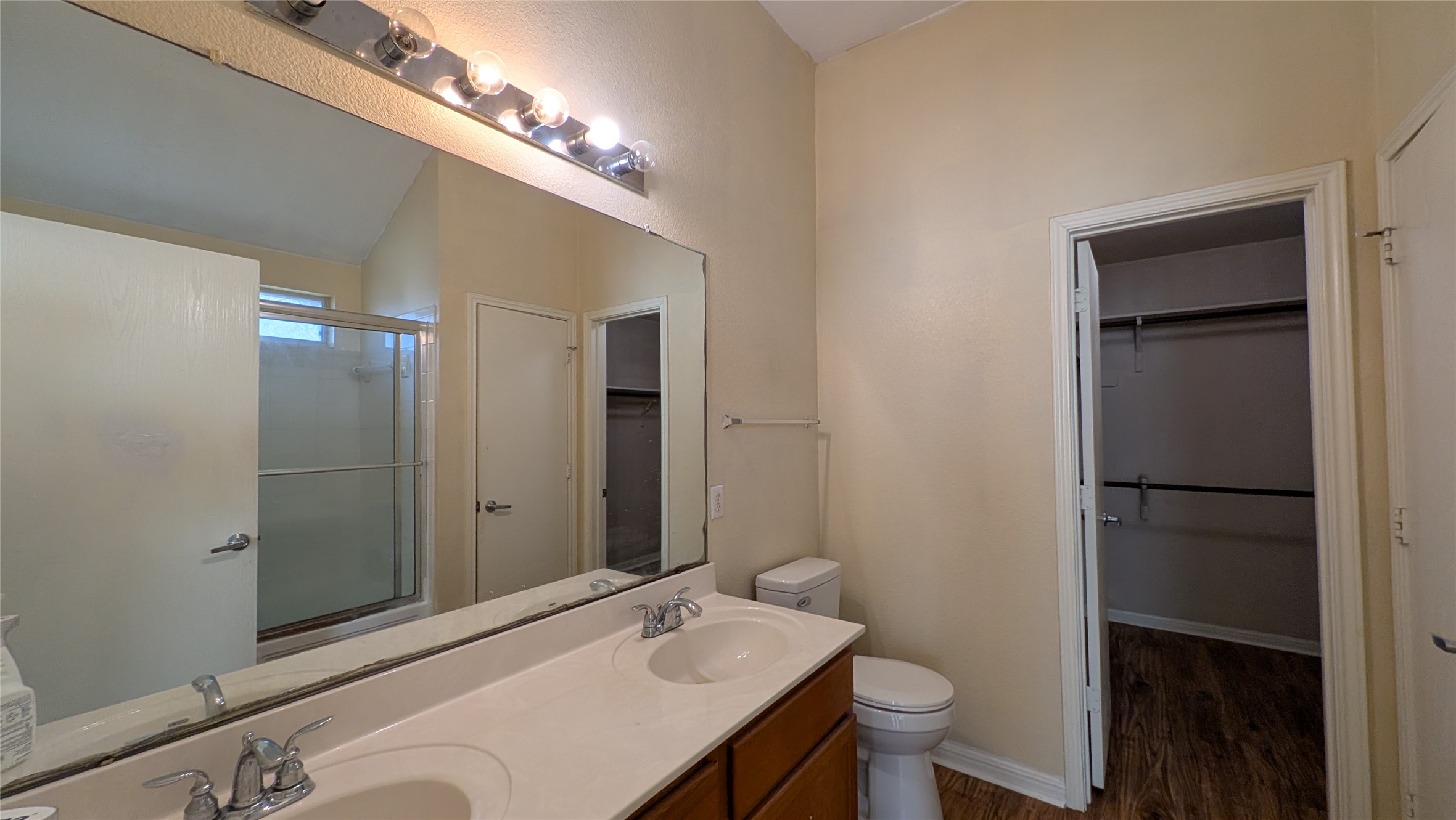 8525 Chick Pea Lane Austin, TX 78745 - Photo 16 of 22 Bathroom with a stall shower, double vanity, a walk in closet, dark wood-type flooring, and vaulted ceiling