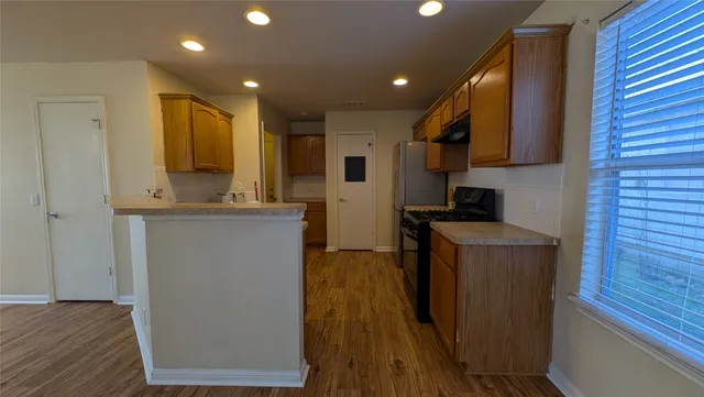 a kitchen with stainless steel appliances granite countertop wooden floors a stove and a microwave