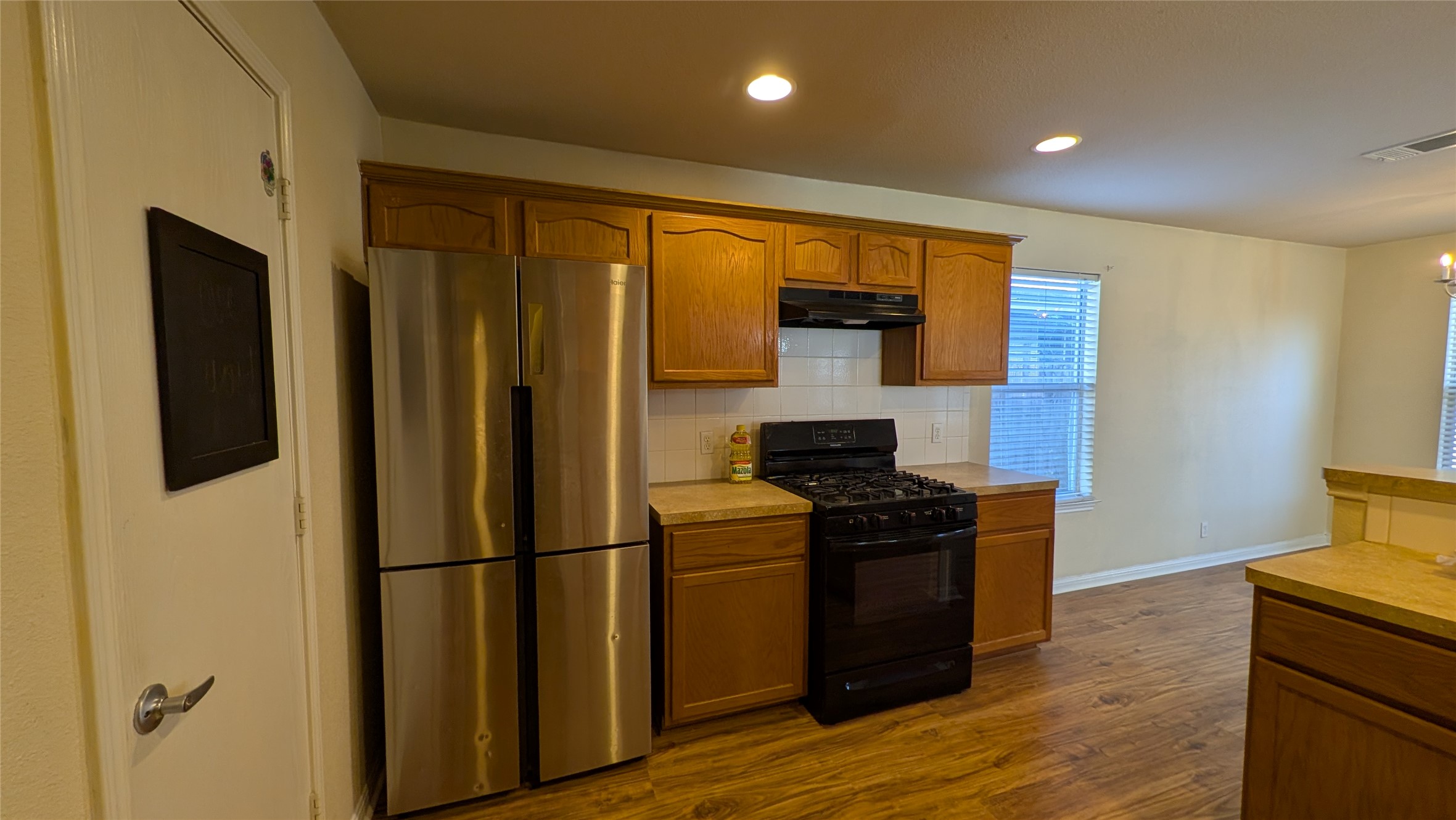 8525 Chick Pea Lane Austin, TX 78745 - Photo 6 of 22 Kitchen with black gas range oven, freestanding refrigerator, light countertops, brown cabinets, and recessed lighting