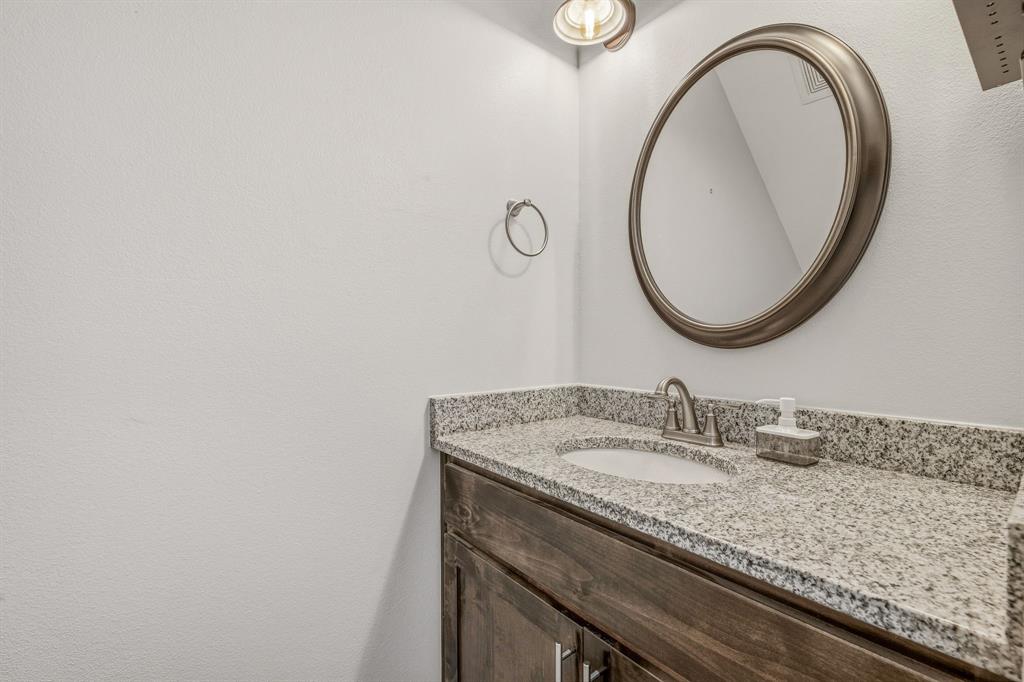 745 North Miller Avenue Stephenville, TX 76401 - Photo 13 of 31 Vanity featuring a stone-finish countertop, undermount sink, and brushed nickel faucet