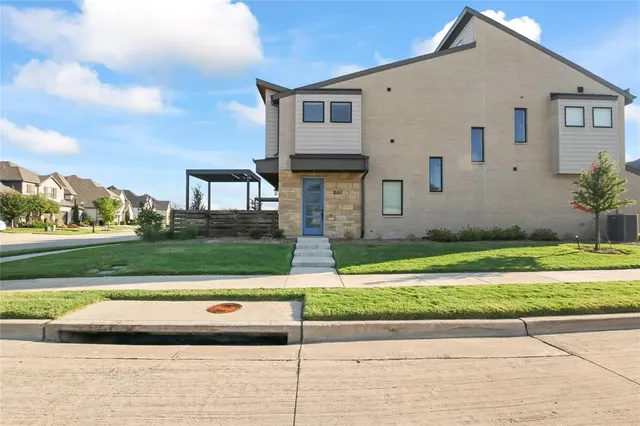 a view of a white house next to a yard with big trees