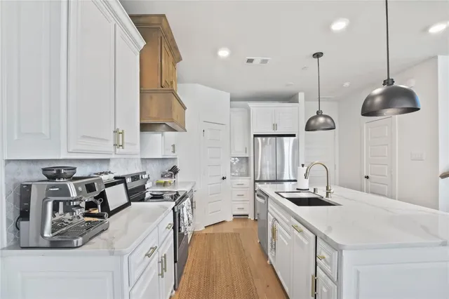 a kitchen with stainless steel appliances a sink a stove and a wooden floors