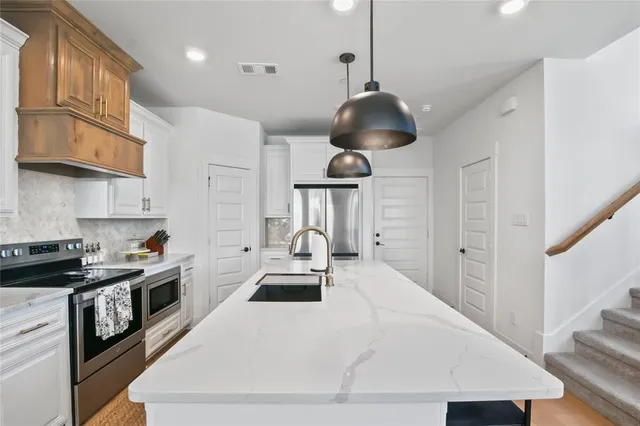 a kitchen with stainless steel appliances a stove a chimney a sink and cabinets