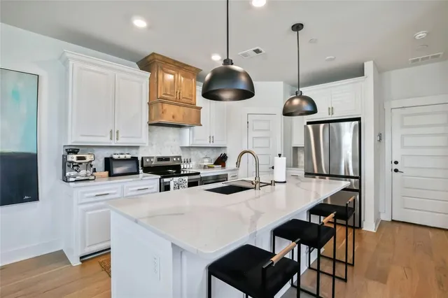 a kitchen with stainless steel appliances a table chairs and a wooden floor