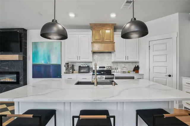 a kitchen with stainless steel appliances a dining table chairs sink and cabinets