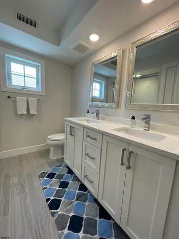 a spacious bathroom with a sink a toilet a mirror and shower