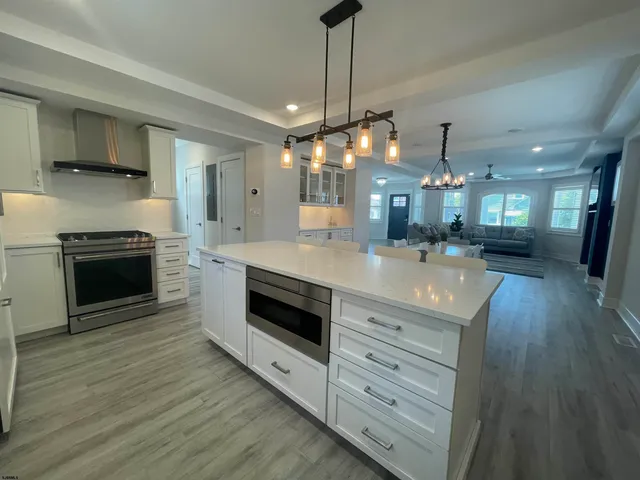 a large kitchen with granite countertop a stove cabinets and wooden floor