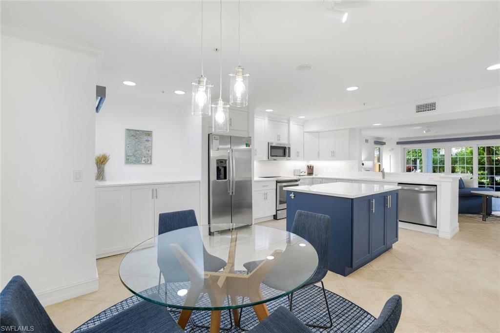 376 3rd Street South, Unit 102 Naples, FL 34102 - Photo 9 of 17 a kitchen with a dining table chairs sink and cabinets