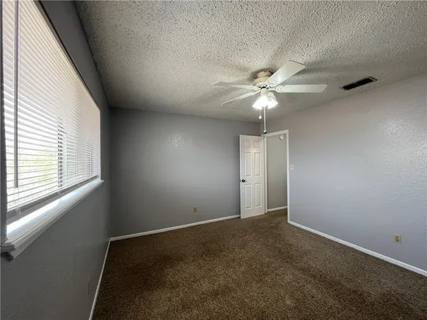 an empty room with windows and fan