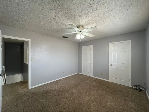 an empty room with fan and windows