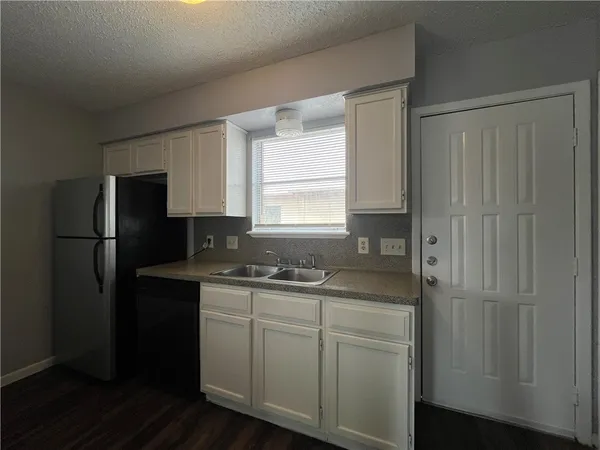 a kitchen with a sink a refrigerator and cabinets