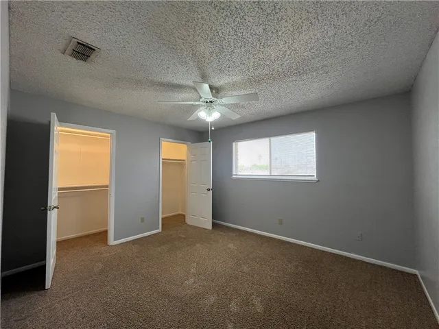 an empty room with windows and chandelier fan