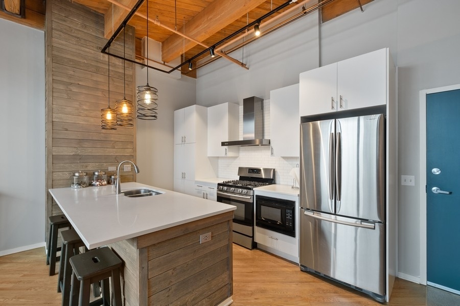 1040 West Adams Street, Unit 239 Chicago, IL 60607 - Photo 4 of 12 a kitchen with stainless steel appliances a refrigerator a sink a stove a dining table and chairs