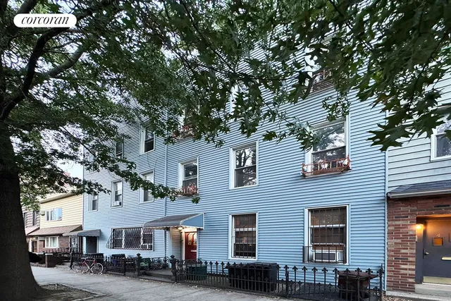 a front view of a building with lot of trees