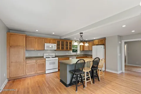 a kitchen with stainless steel appliances granite countertop a kitchen island hardwood floor sink stove dining table and chairs