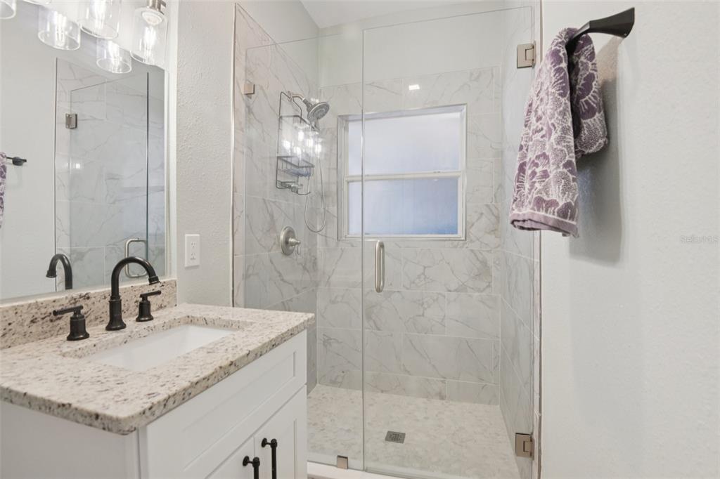 204 160th Avenue Redington Beach, FL 33708 - Photo 17 of 32 a bathroom with a sink vanity granite shower and a mirror