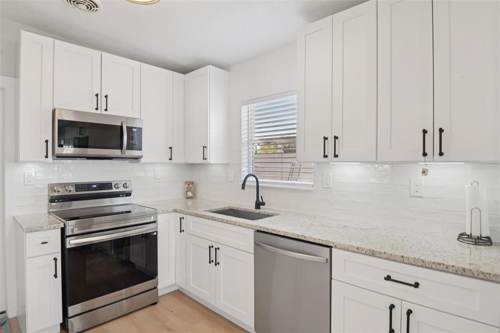 204 160th Avenue Redington Beach, FL 33708 - Photo 6 of 32 a kitchen with granite countertop white cabinets stainless steel appliances and a sink