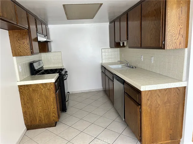 a kitchen with a stove top oven a sink a counter space and cabinets