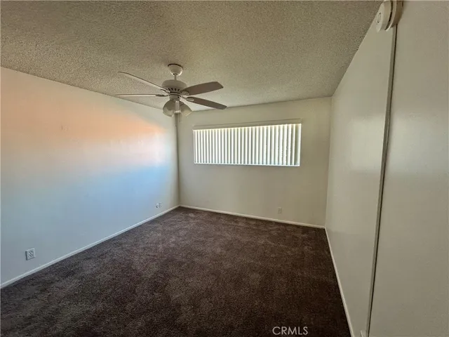 an empty room with a window and a fan