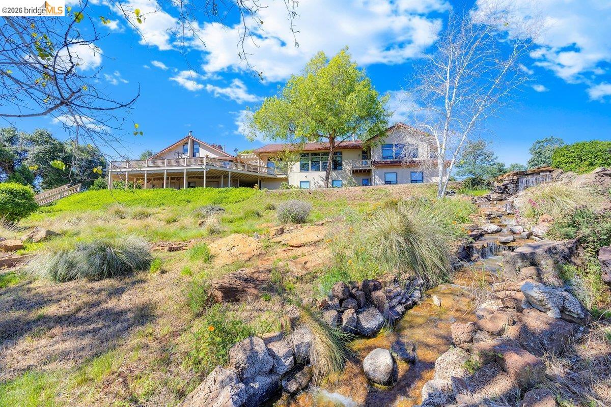 13700 Clements Road Groveland, CA 95321 - Photo 78 of 93 Hillside property featuring a multi-level structure with extensive decking, a naturalistic water feature, and established landscaping