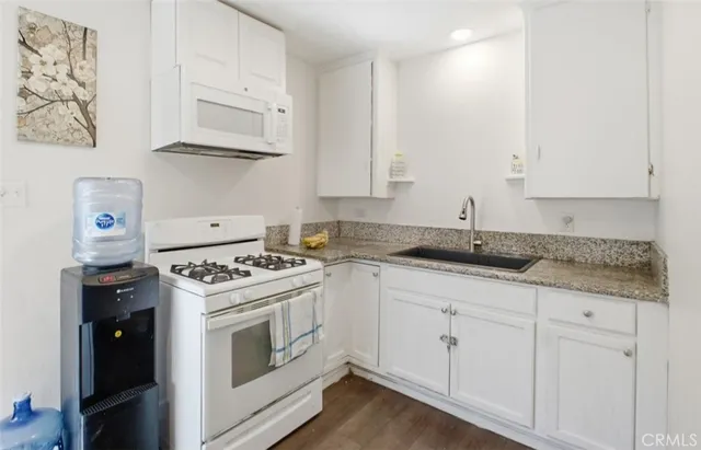 a kitchen with granite countertop white cabinets and white stainless steel appliances