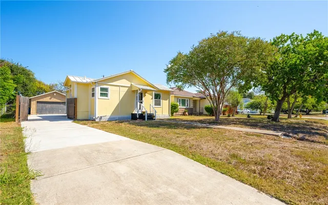 a view of a house with a yard and large tree