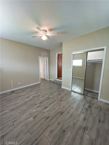 an empty room with wooden floor and mirror on ceiling fan